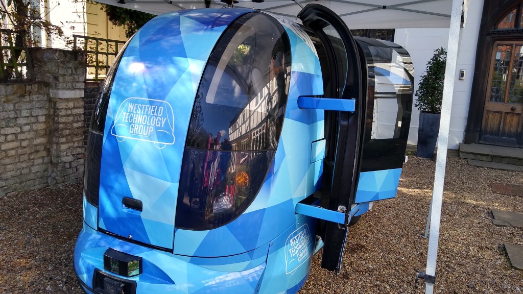 A small, blue vehicle which is symmetrical front to back and which has large bulbous windows on each corner and a double set of passenger doors shown open.