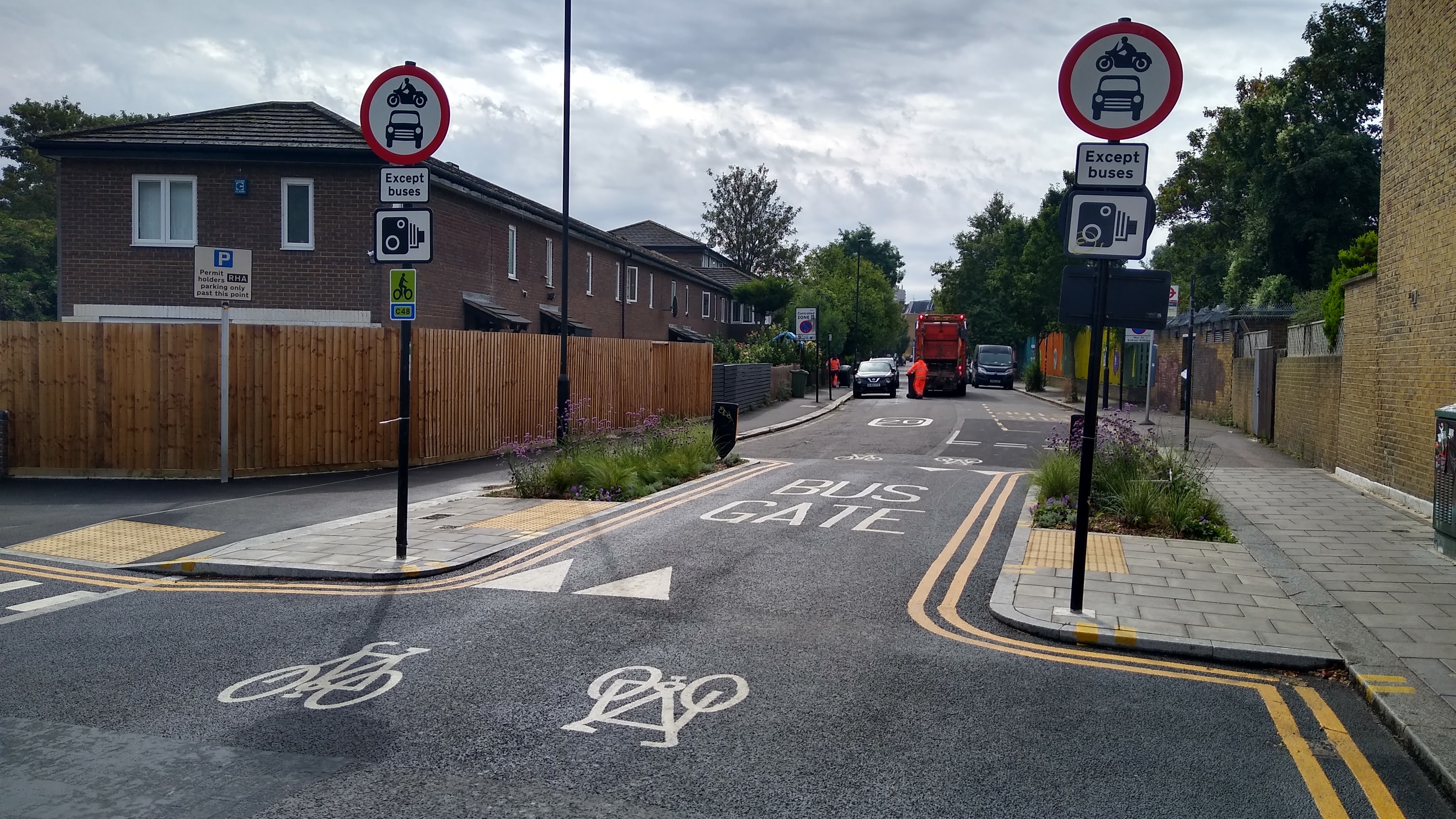 A street scene showing road signs indicating restrictions for vehicles, including "no motor vehicles" signs at a narrowing with planting on both sides.